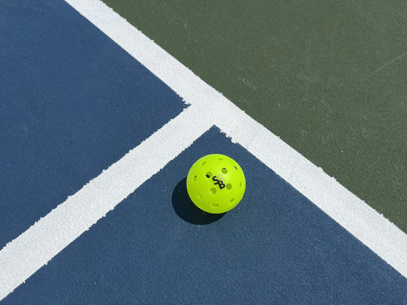 A pickleball resting on a court line